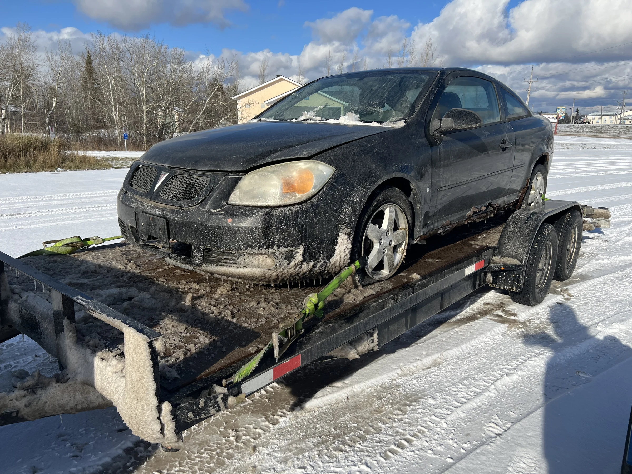 Dirty black coupe on trailer