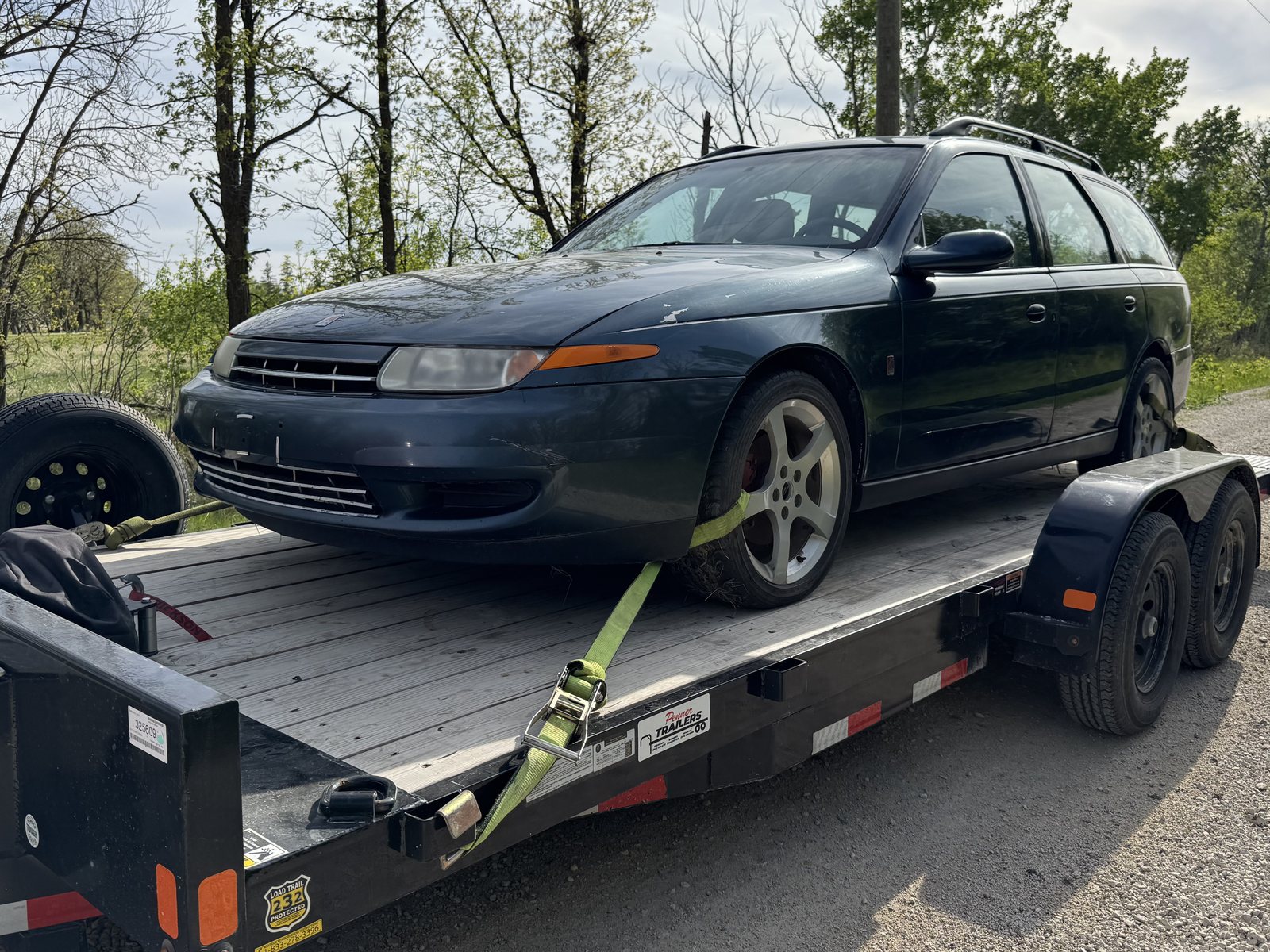 Station wagon strapped down on a flatbed trailer, ready to leave