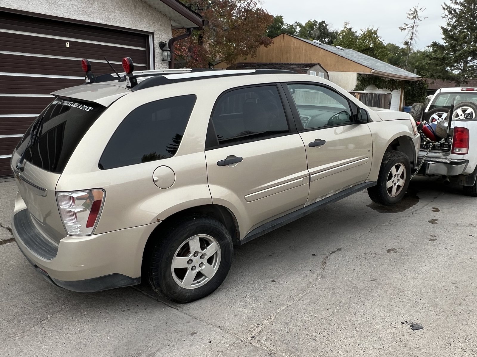 SUV hooked up behind a pickup truck, leaving a driveway